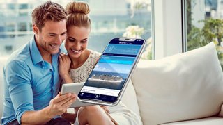 Ein Paar genießt es, gemeinsam ihre Kreuzfahrterfahrung zu planen und verwendet dabei ein Tablet in einer hellen, einladenden Umgebung | MSC Cruises