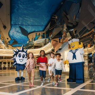 Children and adults walk beside animated characters in a spacious cruise atrium | MSC Cruises