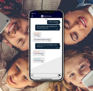 Eine Gruppe lächelnder Freunde um einen Smartphone mit einer Kommunikations-App | MSC Cruises