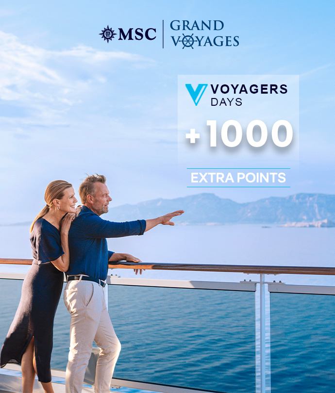 Couple standing on ship deck looking out at the sea under a clear blue sky | MSC Cruises