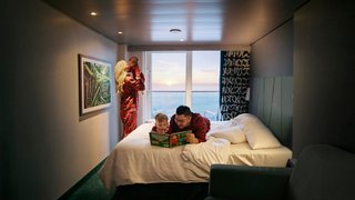 Guests relax in a comfortable cabin with a large window overlooking the sea | MSC Cruises