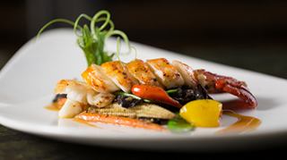 Deliciosa platillo de mariscos decorado con coloridas verduras y hierbas frescas | MSC Cruceros