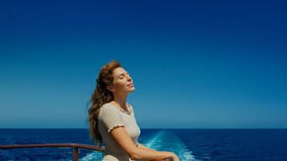 Mujer disfruta de la brisa marina bajo el cielo azul claro | MSC Cruceros