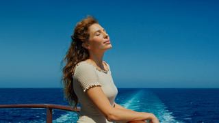 Donna che si gode il sole sul ponte con il mare sullo sfondo | MSC Crociere