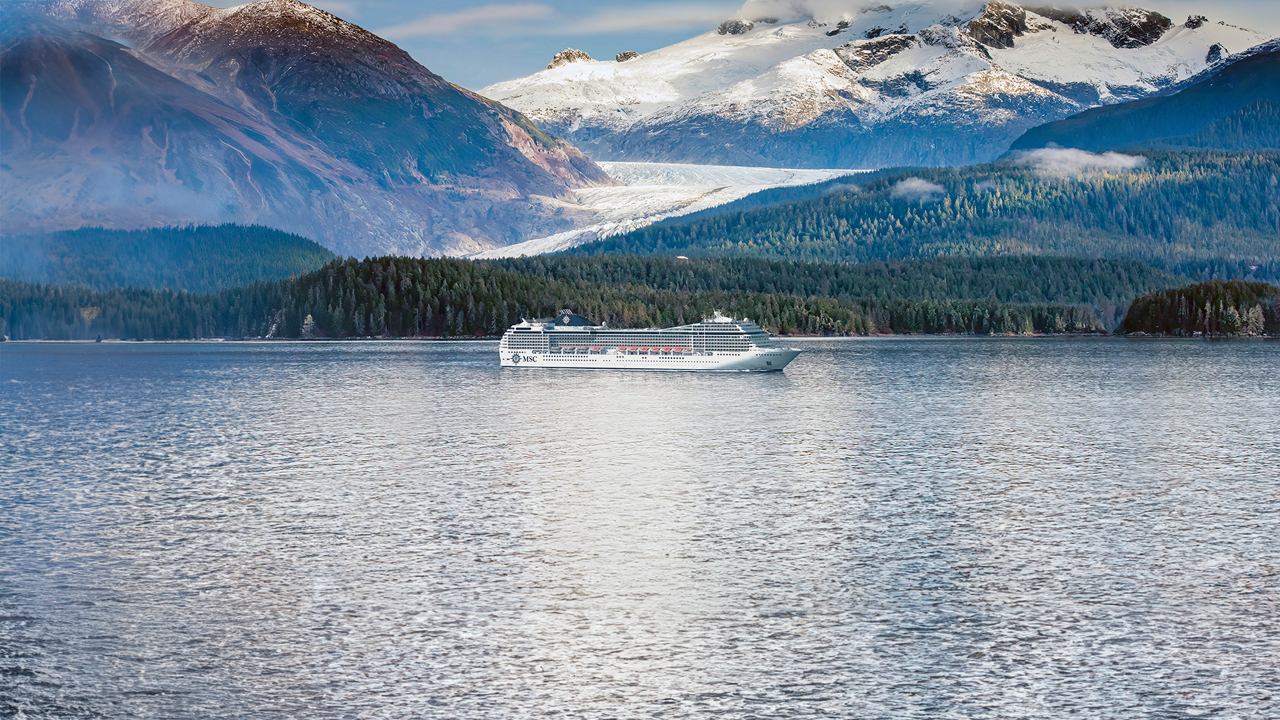 Der ruhige See spiegelt majestätische Berge unter dem blauen Himmel wider | MSC Cruises