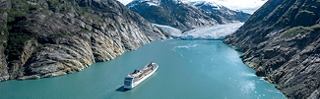 Ein Kreuzfahrtschiff fährt auf einem türkisfarbenen Fluss zwischen eindrucksvollen Bergen | MSC Cruises