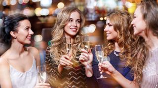 A joyful group of women toasting with champagne glasses in a vibrant nightlife setting | MSC Cruises