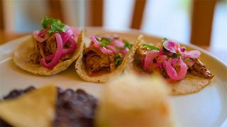Tacos de viande, garnis d'oignons rouges et d'herbes, servis avec du pain et des haricots | MSC Croisières