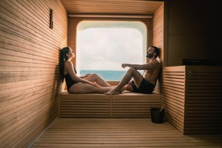 A couple enjoys the view from a cozy room with a window overlooking the sea | MSC Cruises