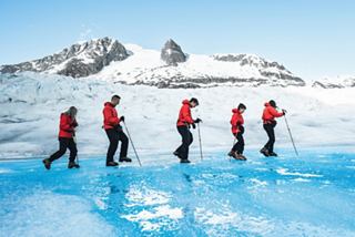 Reisende in roten Jacken erkunden eine Eislandschaft vor schneebedeckten Bergen | MSC Cruises
