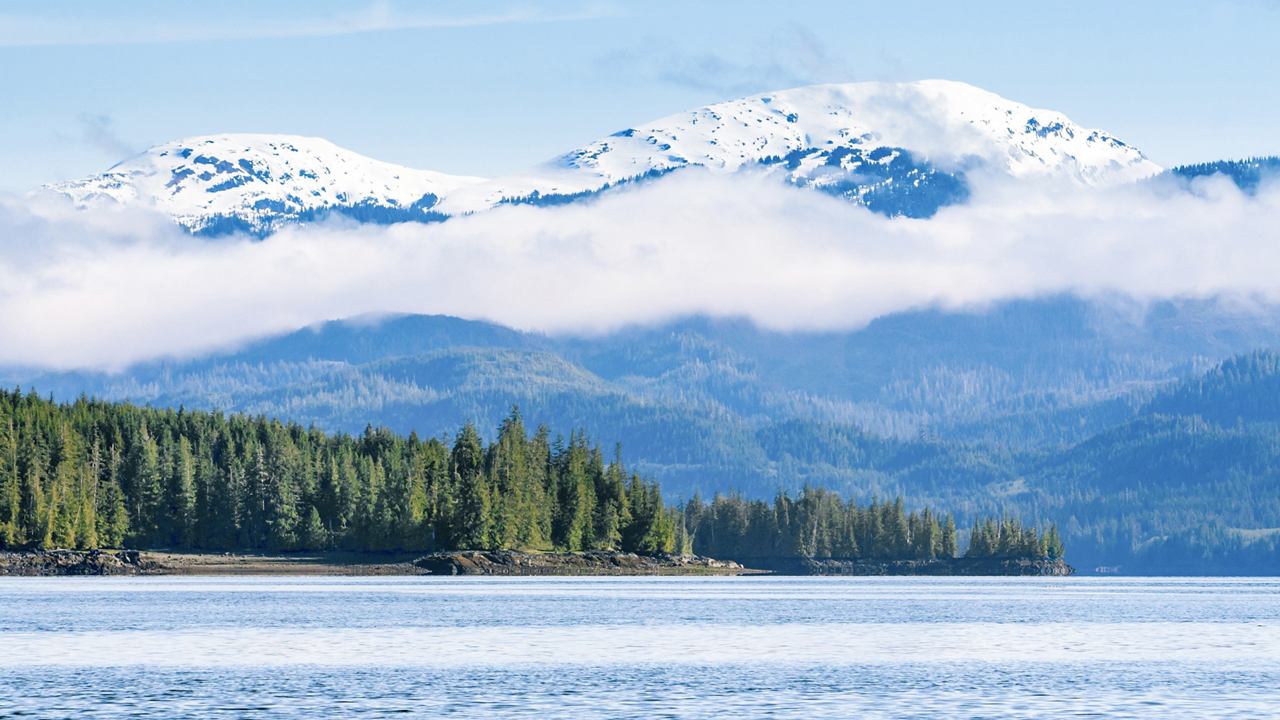 Mer calme avec des montagnes et des nuages au-dessus de Carroll Inlet en Alaska | MSC Croisières