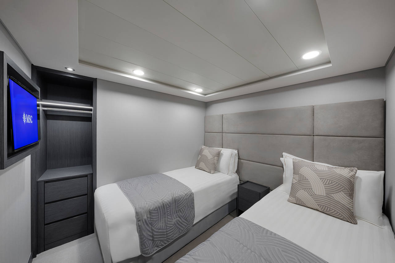 Bright room with two beds and a TV on the wall | MSC Cruises