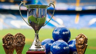 The trophy stands proudly with golden football boots in front of a football stadium backdrop | MSC Cruises