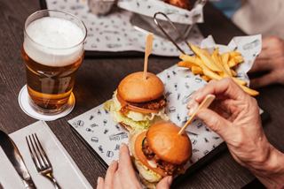 Two chicken sliders, fries and a glass of beer arranged on a dining table | MSC Cruises
