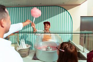 Staff hands cotton candy to a child and adult in a modern dining area | MSC Cruises