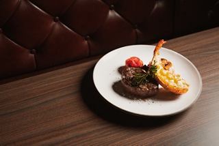 Steak served with vegetables and fries on a white plate placed on a dining table | MSC Cruises