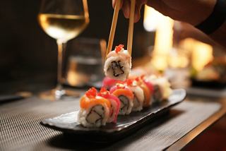 Sushi rolls served on a platter with chopsticks and a glass of white wine on the table | MSC Cruises