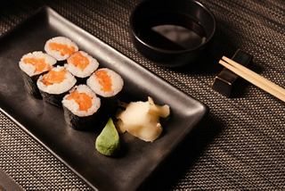Salmon sushi rolls with wasabi and ginger arranged on a black serving tray | MSC Cruises