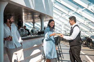 Guests enjoy drinks and food at the MSC Yacht Club bar on MSC World Europa | MSC Cruises