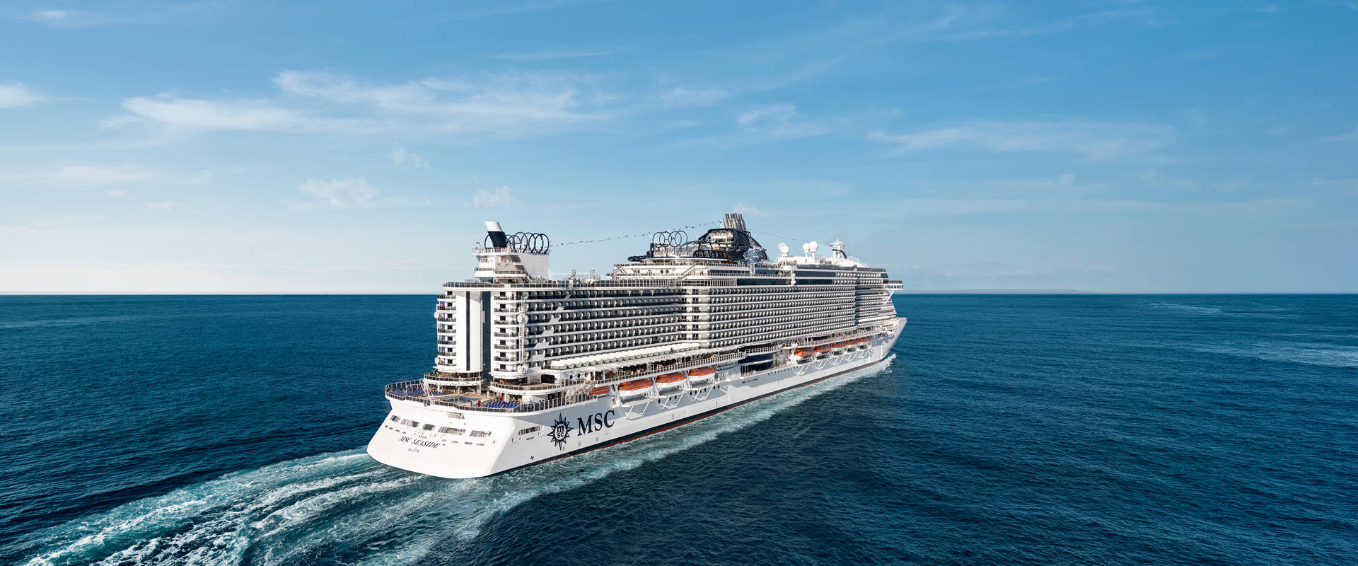 MSC Seaside cruise ship sails across open blue sea under a clear sky | MSC Cruises