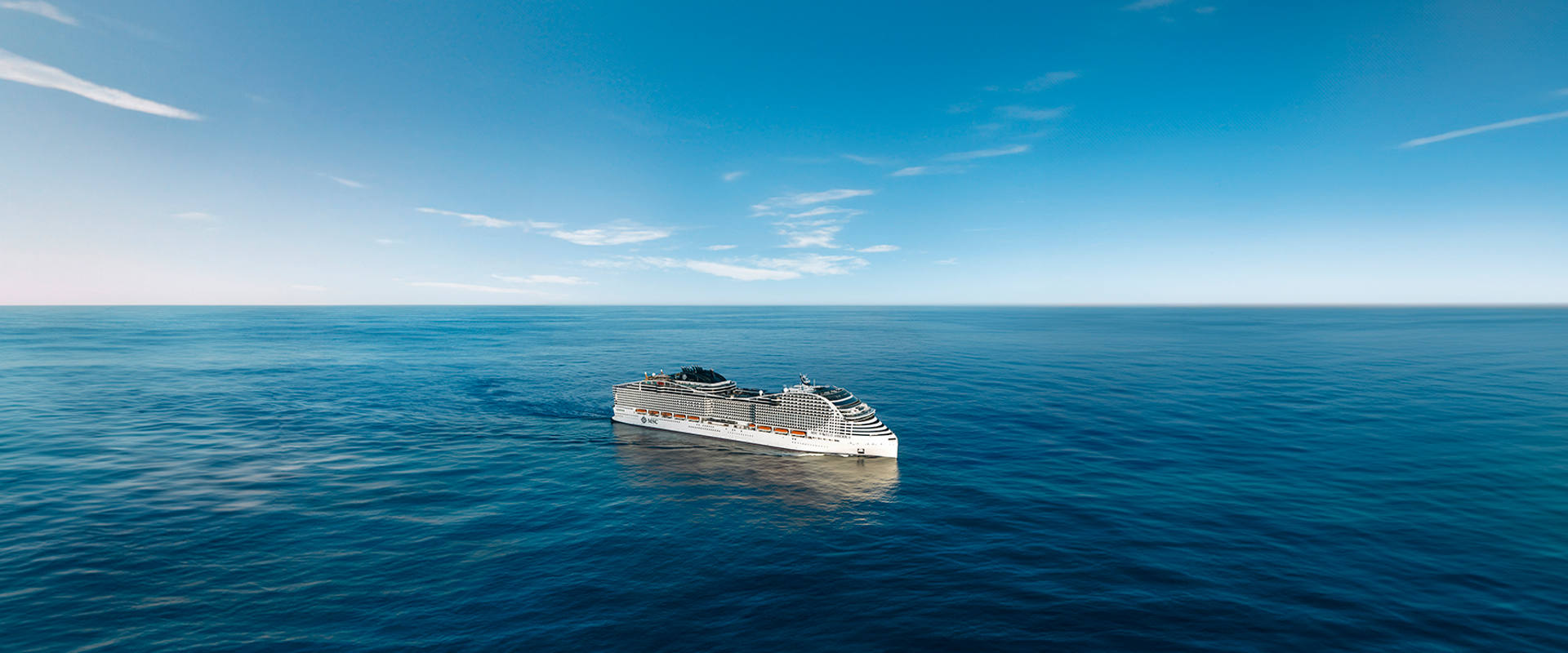 MSC World America sails across a vast blue sea beneath a clear and expansive sky | MSC Cruises
