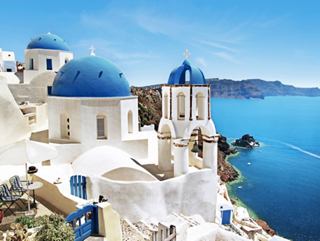 Stunning view of white buildings with domes in Santorini, Greece, beside the blue sea | MSC Cruises