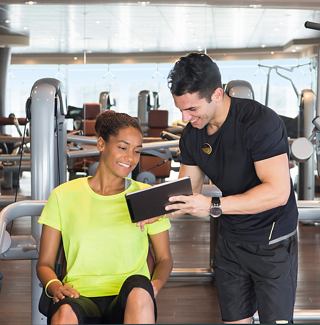 A personal trainer assists a client with their workout routine in a modern gym setting | MSC Cruises