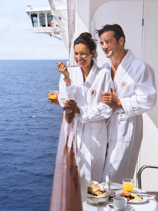 Zwei Personen im Bademantel genießen Getränke auf einem Balkon mit Meerblick | MSC Cruises