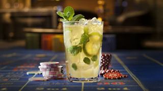 A refreshing cocktail garnished with mint leaves sits on a vibrant bar surface | MSC Cruises
