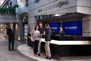 A welcoming crew assists guests at the MSC Meraviglia desk in the Galleria Meraviglia | MSC Cruises