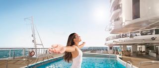 A joyful woman embraces the sun by the pool, enjoying life on board the MSC Seaside with the sea in the background | MSC Cruises