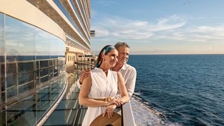 A happy couple enjoys a romantic moment together on a cruise ship with the ocean in the background | MSC Cruises