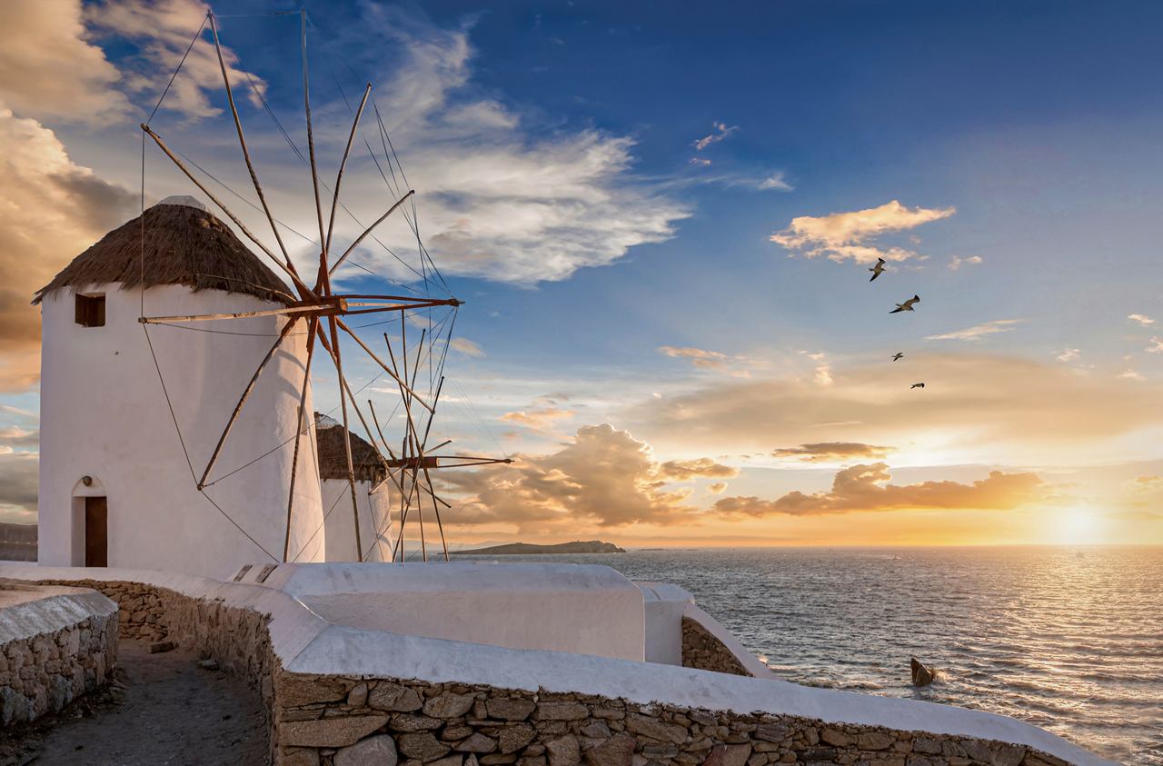 Un mulino a vento con il tramonto sul mare a Mykonos, Grecia | MSC Crociere