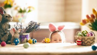 Niño con orejas de conejo asomándose detrás de decoraciones y huevos de Pascua | MSC Cruceros