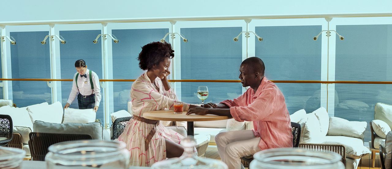 Zwei Freunde genießen einen Kaffee an Bord eines Kreuzfahrtschiffs mit Blick auf das Meer | MSC Cruises