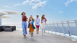 A family enjoys a stroll on a cruise ship deck beneath a bright blue sky and ocean view | MSC Cruises