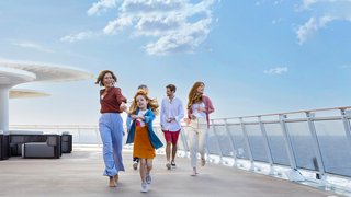 A family enjoys a stroll along the sunny deck of a cruise ship overlooking the sea | MSC Cruises