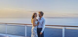 Young man and woman enjoying sea breeze on ship deck with palm trees in the background | MSC Cruises