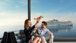 A couple joyfully toasting with drinks, enjoying a scenic view from their cruise ship | MSC Cruises