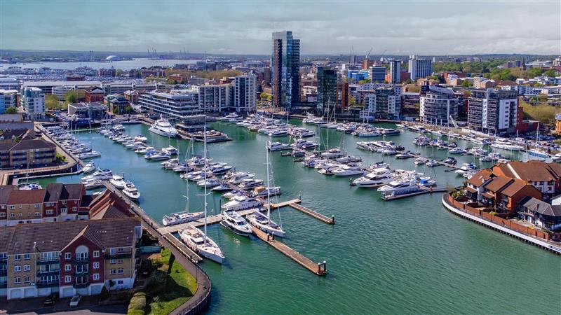 A vibrant harbour filled with boats, surrounded by a bustling city skyline under a clear blue sky | MSC Cruises