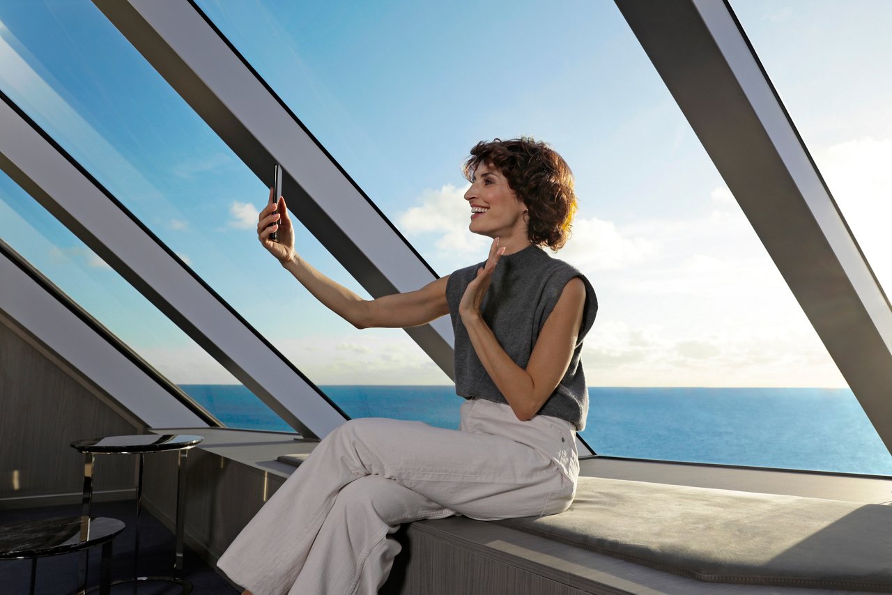 Woman with a smartphone enjoying the sea view through a glass wall | MSC Cruises