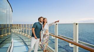 A couple joyfully embracing on a ship's balcony, overlooking a serene ocean view | MSC Cruises