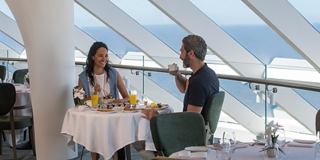 A couple enjoys drinks and conversation in a restaurant with a sea view | MSC Cruises