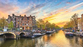 Sunset over Amsterdam's canals with beautiful buildings in the background | MSC Cruises