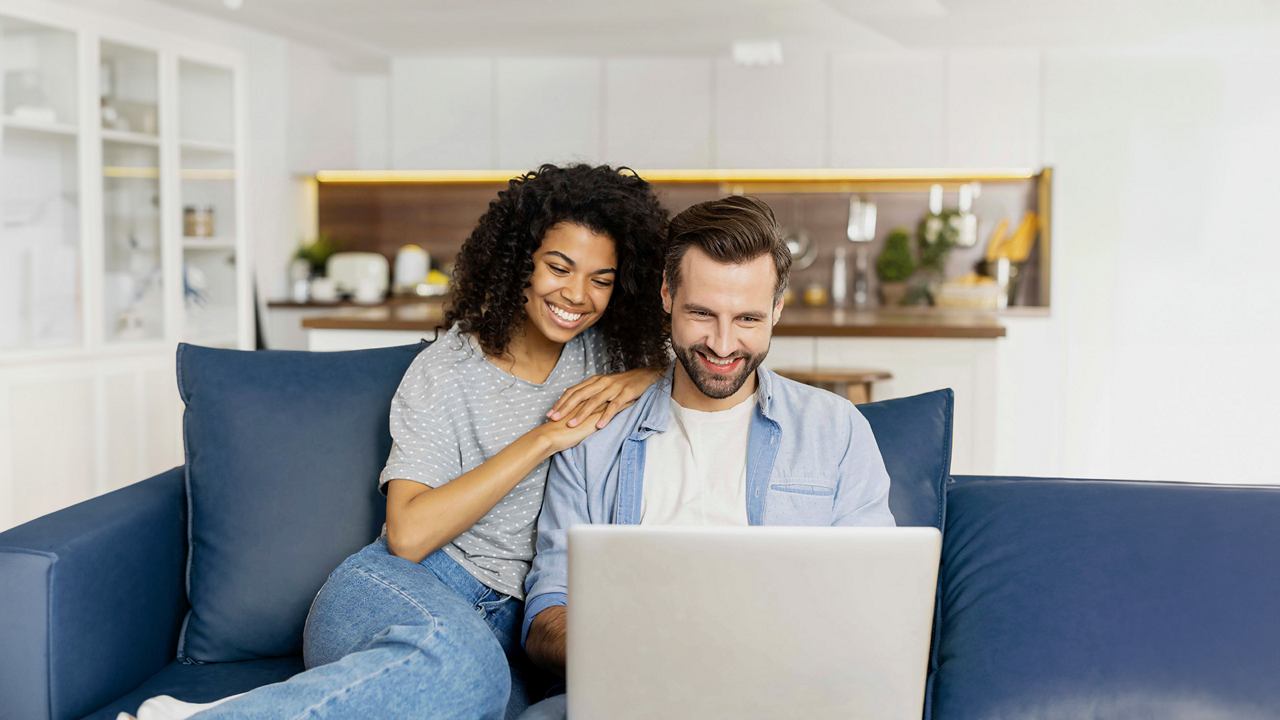 Ein Paar genießt es, ihr nächstes Abenteuer gemeinsam auf einem bequemen Sofa mit einem Laptop zu planen | MSC Cruises