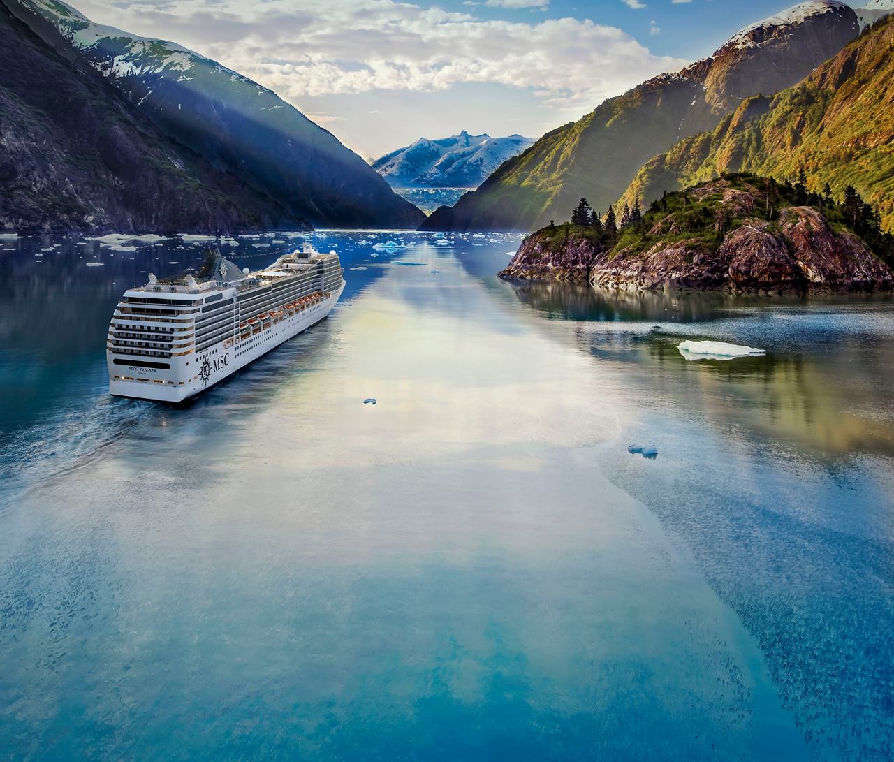 A cruise ship sails through the tranquil waters of Tracy Arm, surrounded by majestic mountains and glaciers | MSC Cruises