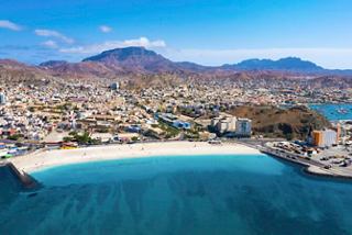 Aerial view of Mindelo in Cape Verde featuring Laginha Beach, blue sea, and surrounding mountains under a bright sky | MSC Cruises