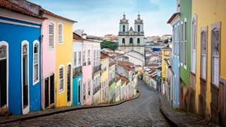 A vibrant street in Salvador de Bahia, showcasing colourful buildings and the majestic church in the background | MSC Cruises