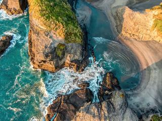 Aerial view of waves crashing against a rocky coastline at sunset in Auckland, New Zealand | MSC Cruises