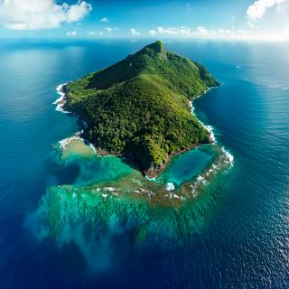 Aerial view of Pitcairn Island showcasing the vibrant sea and lush greenery surrounding Saint Paul's Pool | MSC Cruises